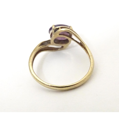 610 - A 9ct gold ring set with central amethyst flanked by diamonds. Ring size approx. R