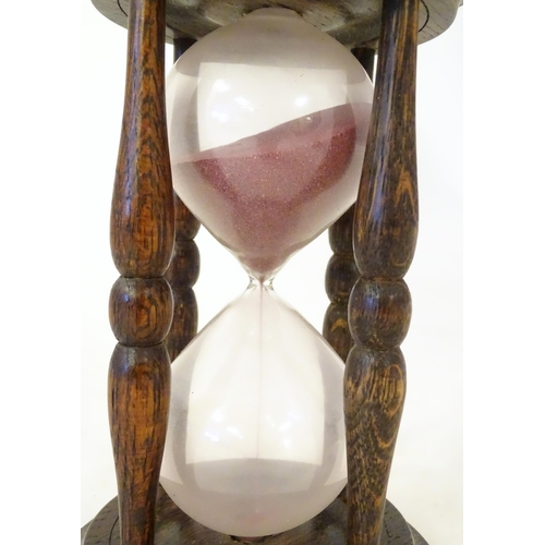 1255 - An early 20thC hourglass / sand timer with turned wooden ends supported by four turned treen columns... 