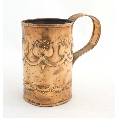 995 - An Art Nouveau copper tankard with loop handle, decorated with embossed floral decoration and banded... 