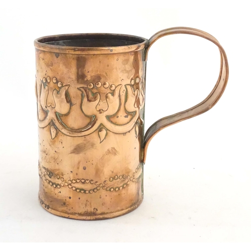 995 - An Art Nouveau copper tankard with loop handle, decorated with embossed floral decoration and banded... 