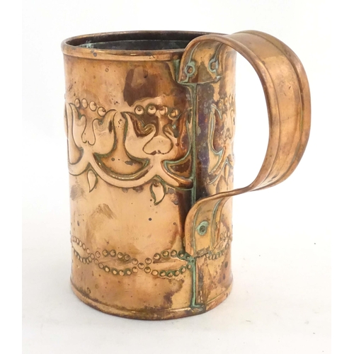 995 - An Art Nouveau copper tankard with loop handle, decorated with embossed floral decoration and banded... 