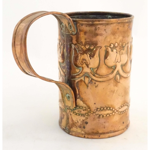 995 - An Art Nouveau copper tankard with loop handle, decorated with embossed floral decoration and banded... 