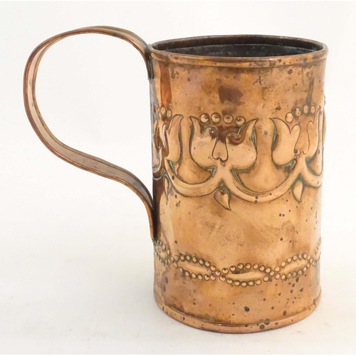 995 - An Art Nouveau copper tankard with loop handle, decorated with embossed floral decoration and banded... 