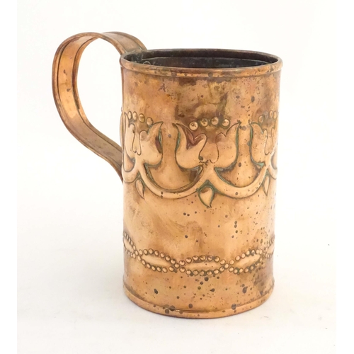 995 - An Art Nouveau copper tankard with loop handle, decorated with embossed floral decoration and banded... 