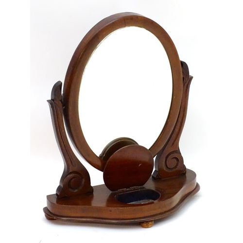 35 - A Victorian mahogany toilet mirror with an oval mirror and shaped surrounds above a moulded base wit... 