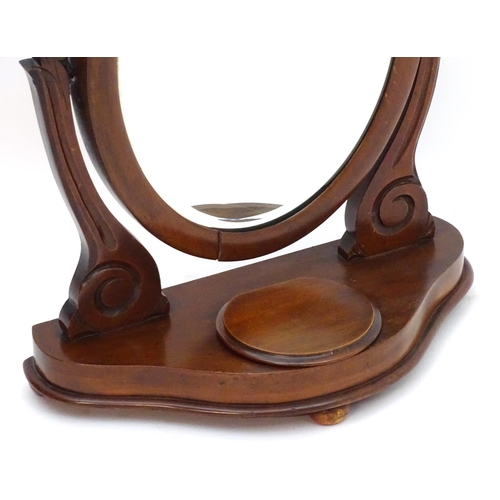 35 - A Victorian mahogany toilet mirror with an oval mirror and shaped surrounds above a moulded base wit... 