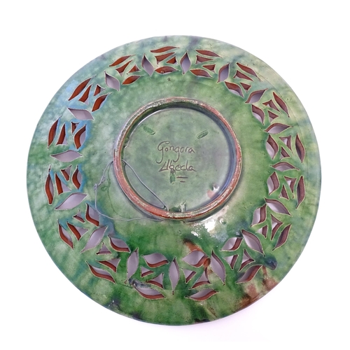 71 - A Spanish terracotta Gongora Ubeda charger with a green glaze, pierced decoration and stylised cocke... 