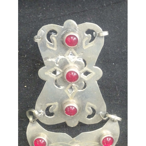 76 - A white metal pendant with red cabochon detail. Possibly Indian  within shadow box frame. Approx 7