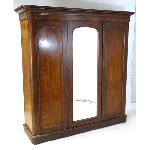 140 - A Victorian mahogany triple wardrobe with a moulded cornice above a central mirrored door and two ar... 