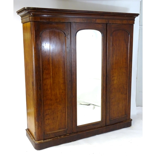 140 - A Victorian mahogany triple wardrobe with a moulded cornice above a central mirrored door and two ar... 