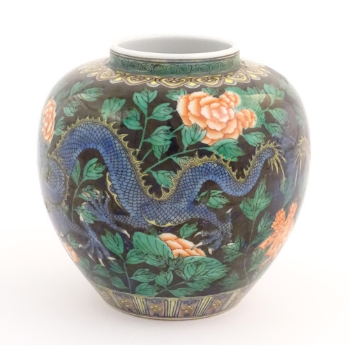 31 - A Chinese famille noir vase decorated with two dragons and a flaming pearl amongst flowers and folia... 