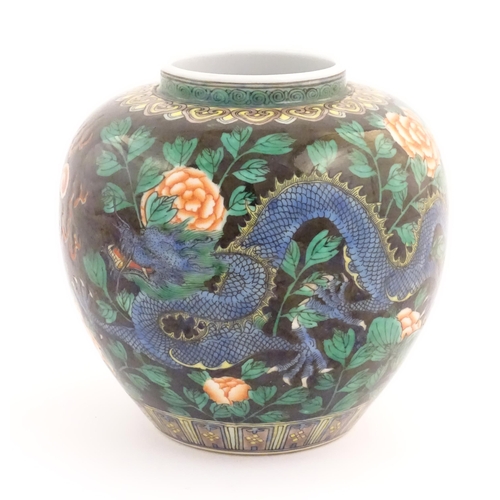 31 - A Chinese famille noir vase decorated with two dragons and a flaming pearl amongst flowers and folia... 