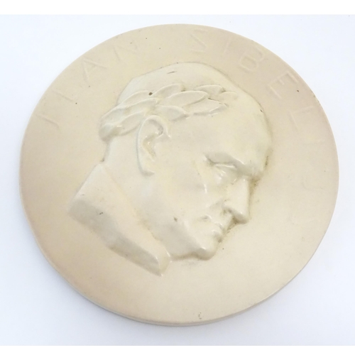 45A - A 20thC Arabia ceramic roundel / plaque depicting a portrait of the Finnish composer Jean Sibelius w... 