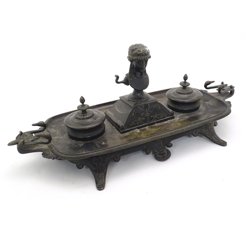 1025 - A 19thC Continental bronze desk standish with twin handles modelled with swan heads, the central Cla... 