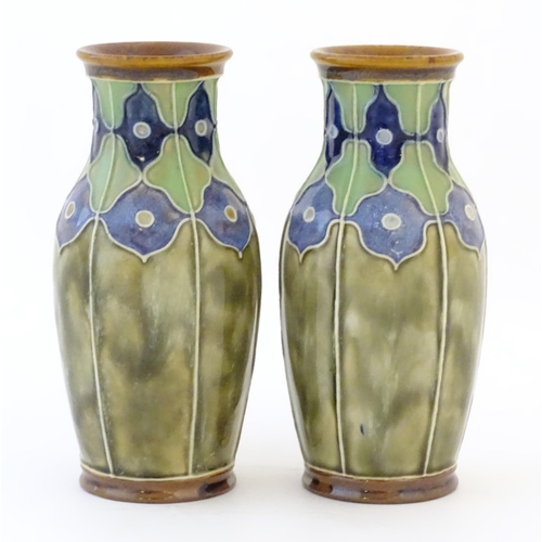 86 - A pair of Royal Doulton vases decorated with stylised floral detail and tube lining. Marked under, w... 