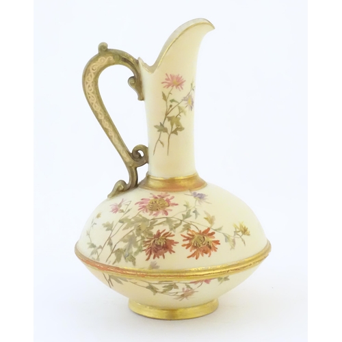 90 - A Royal Worcester jug / ewer with a cream ground, floral decoration and gilt highlights. Marked unde... 