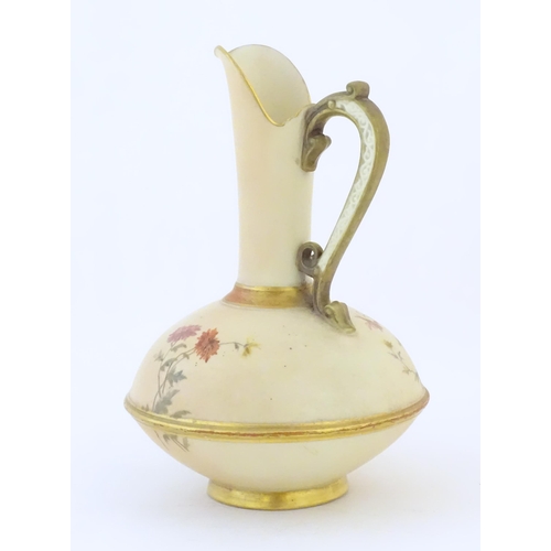 90 - A Royal Worcester jug / ewer with a cream ground, floral decoration and gilt highlights. Marked unde... 