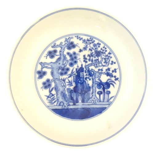 11 - A Chinese blue and white plate decorated with trees and flowers, the reverse decorated with figures ... 