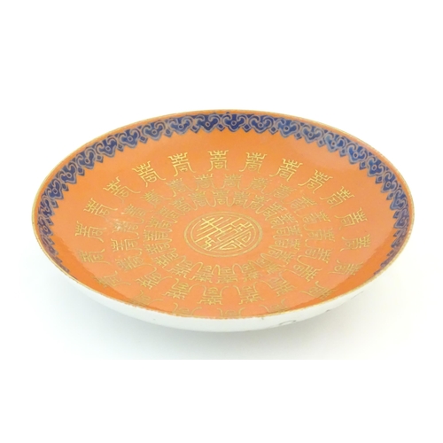 14 - A Chinese plate with an orange ground and gilt decoration with a blue border. The reverse decorated ... 