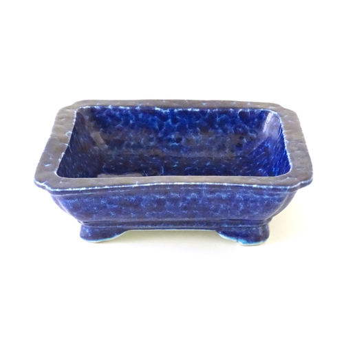25 - A Chinese dish of rectangular form with a blue glaze, raised on four feet. Character marks under. Ap... 