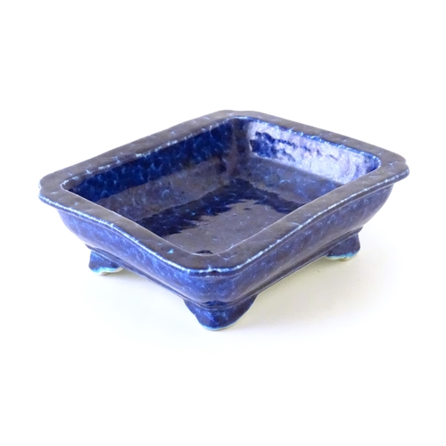 25 - A Chinese dish of rectangular form with a blue glaze, raised on four feet. Character marks under. Ap... 