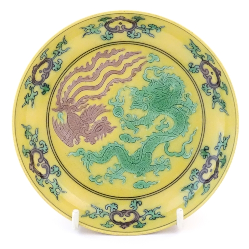 4 - A small Chinese plate with a yellow ground with dragon and phoenix bird decoration. Character marks ... 