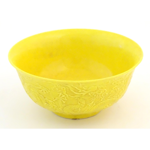 9 - A Chinese bowl with a yellow ground decorated in relief with dragons amongst stylised clouds. Charac... 