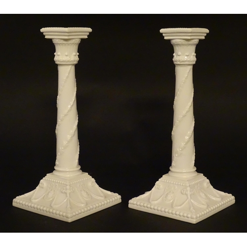 94 - A pair of Royal Worcester candlesticks with relief twist decoration to columns and swag detail to sq... 