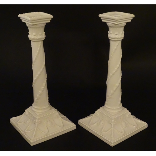 94 - A pair of Royal Worcester candlesticks with relief twist decoration to columns and swag detail to sq... 