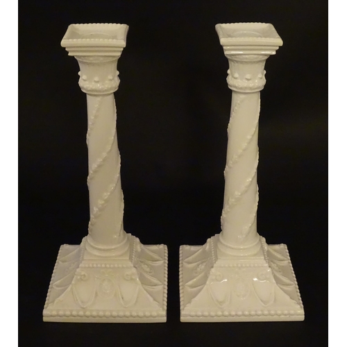 94 - A pair of Royal Worcester candlesticks with relief twist decoration to columns and swag detail to sq... 