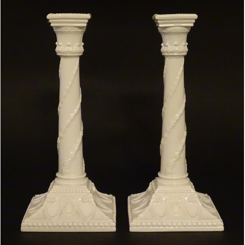 94 - A pair of Royal Worcester candlesticks with relief twist decoration to columns and swag detail to sq... 