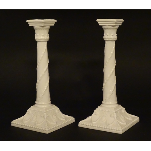 94 - A pair of Royal Worcester candlesticks with relief twist decoration to columns and swag detail to sq... 