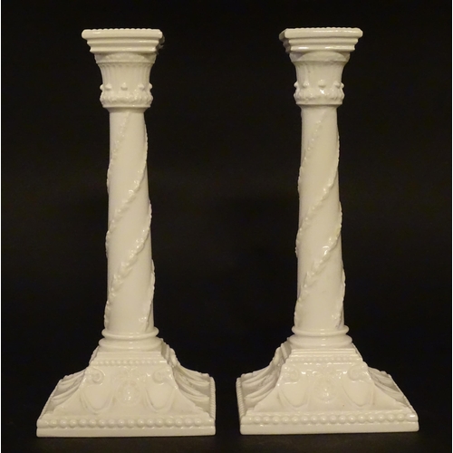 94 - A pair of Royal Worcester candlesticks with relief twist decoration to columns and swag detail to sq... 