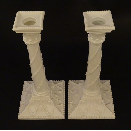 94 - A pair of Royal Worcester candlesticks with relief twist decoration to columns and swag detail to sq... 