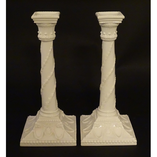 94 - A pair of Royal Worcester candlesticks with relief twist decoration to columns and swag detail to sq... 