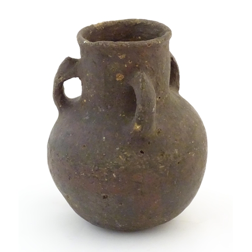 57 - A pottery three handled vase with a bulbous body in the manner of a bronze age drinking vessel. Appr... 