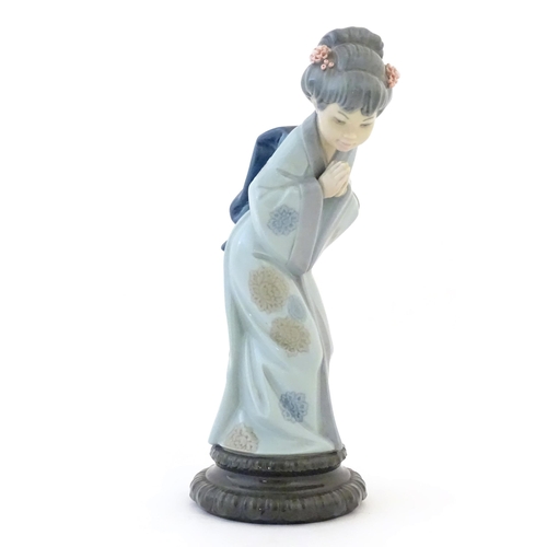 83 - A Lladro model of a Japanese Geisha girl bowing with her hands together, model no. 4989. Marked unde... 