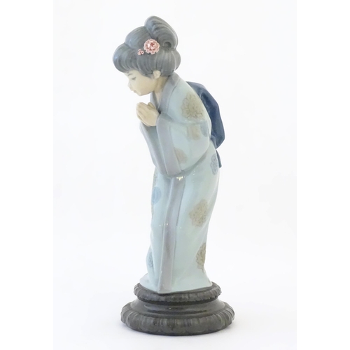 83 - A Lladro model of a Japanese Geisha girl bowing with her hands together, model no. 4989. Marked unde... 