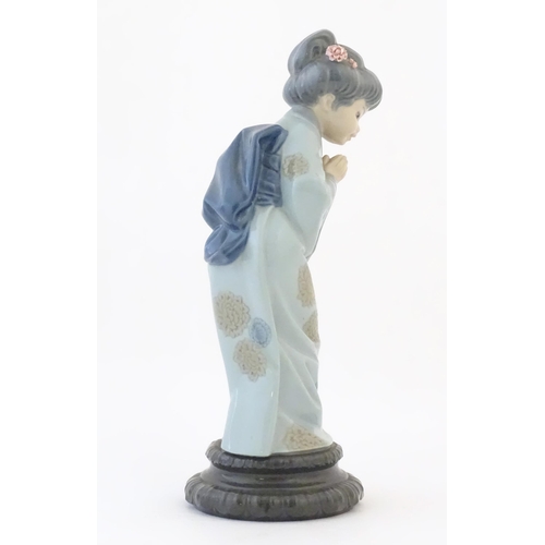 83 - A Lladro model of a Japanese Geisha girl bowing with her hands together, model no. 4989. Marked unde... 