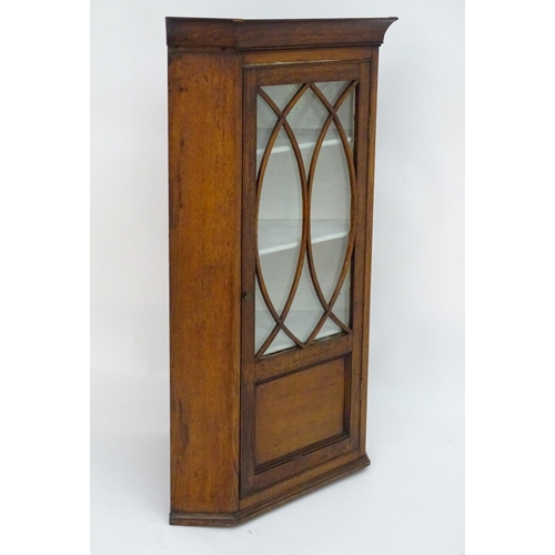 194 - A Victorian hanging oak corner cupboard with a moulded cornice above an astragal glazed door an cont... 