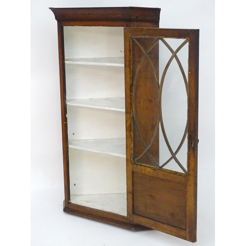 194 - A Victorian hanging oak corner cupboard with a moulded cornice above an astragal glazed door an cont... 