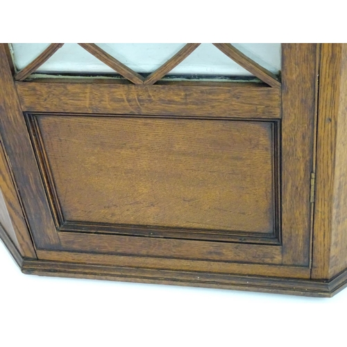 194 - A Victorian hanging oak corner cupboard with a moulded cornice above an astragal glazed door an cont... 