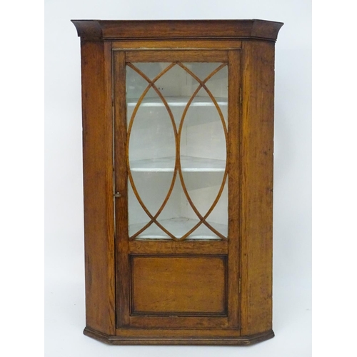 194 - A Victorian hanging oak corner cupboard with a moulded cornice above an astragal glazed door an cont... 