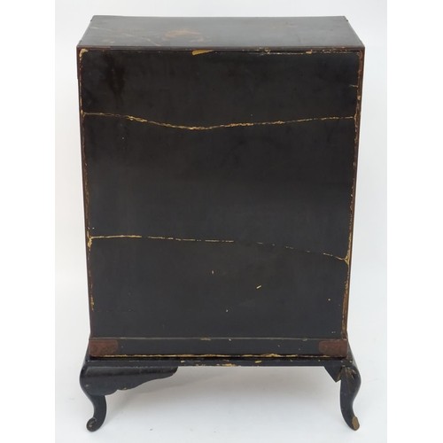 298 - An oriental black lacquered cabinet with carrying handles to the side and resting on a stand. The do... 