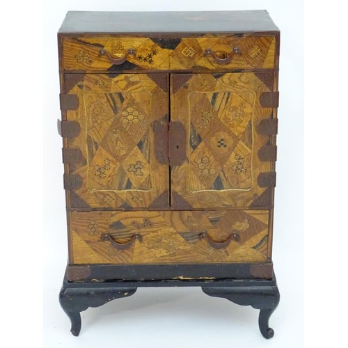 298 - An oriental black lacquered cabinet with carrying handles to the side and resting on a stand. The do... 