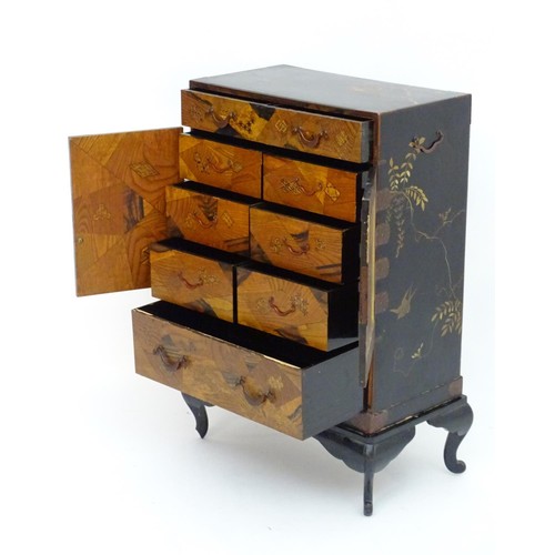 298 - An oriental black lacquered cabinet with carrying handles to the side and resting on a stand. The do... 