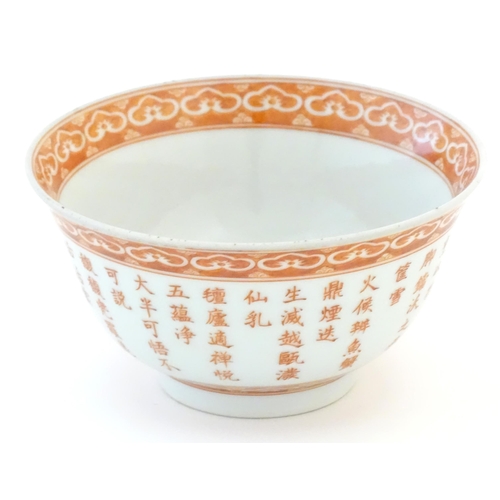 21 - A small Chinese red and white bowl decorated with flowers and foliage, the exterior with character s... 