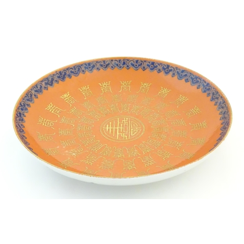 29 - A Chinese plate with an orange ground and gilt decoration with a blue border. The reverse decorated ... 