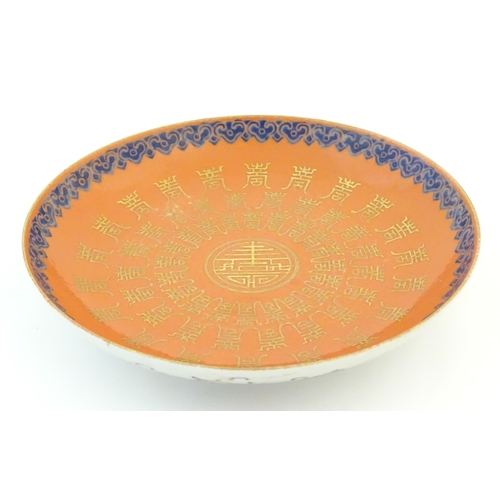 29 - A Chinese plate with an orange ground and gilt decoration with a blue border. The reverse decorated ... 