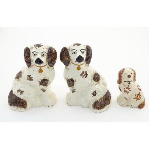 55 - A pair of Staffordshire pottery seated spaniels, together with another smaller example. Largest appr... 